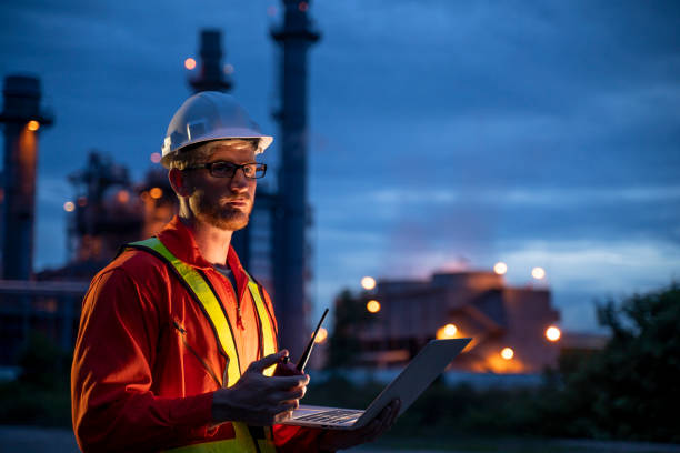 Engineering is use notebook check and standing in front of oil refinery building structure in heavy petrochemical industry